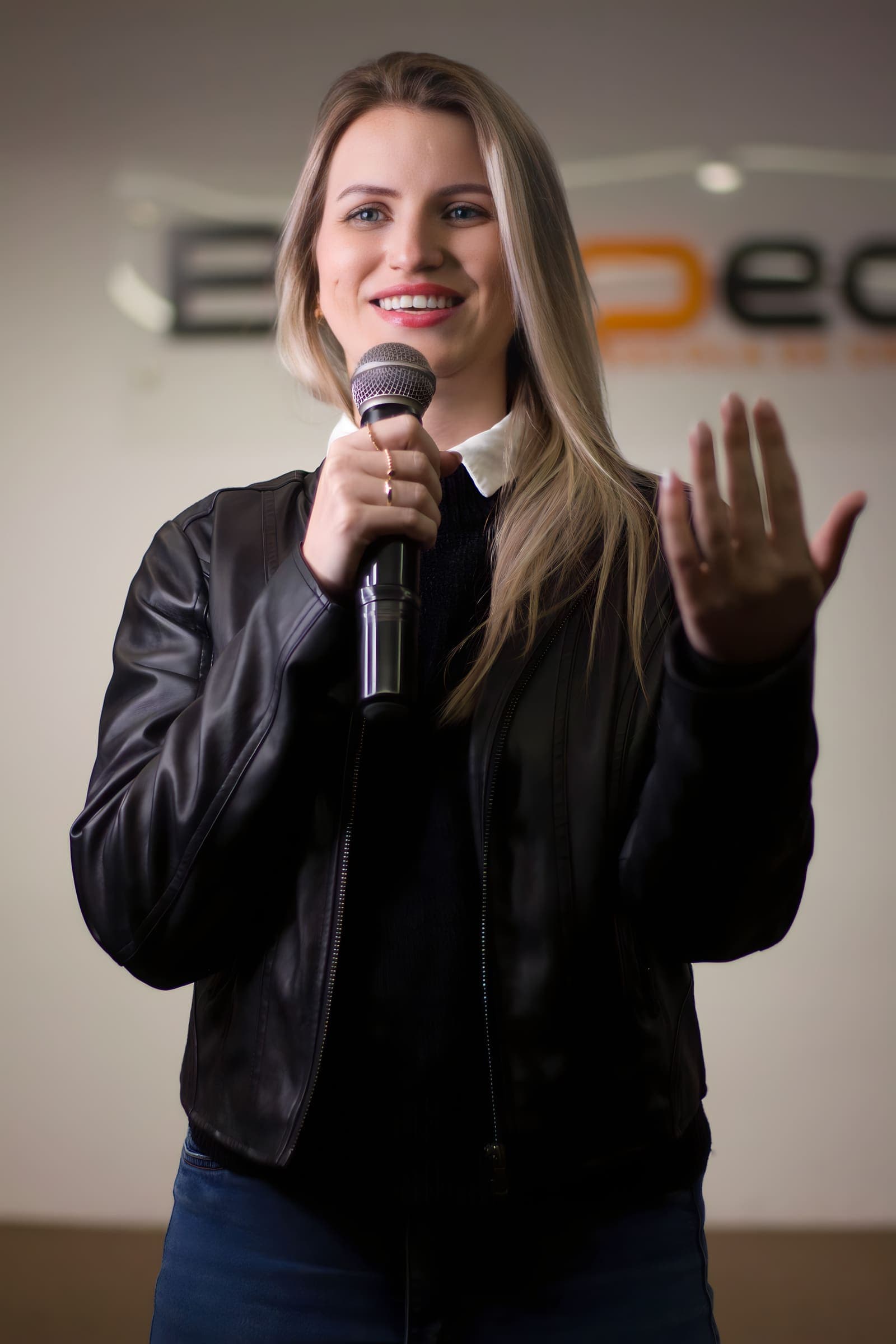 Aluna gesticula com o microfone na mão durante apresentação na Bespeak