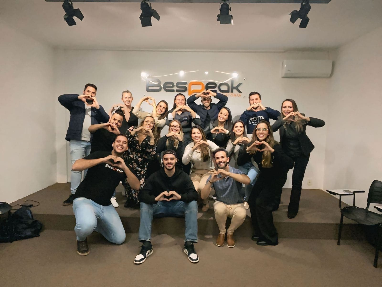 Turma da Bespeak Passo Fundo reunida em frente ao palco, fazendo coração com as mãos